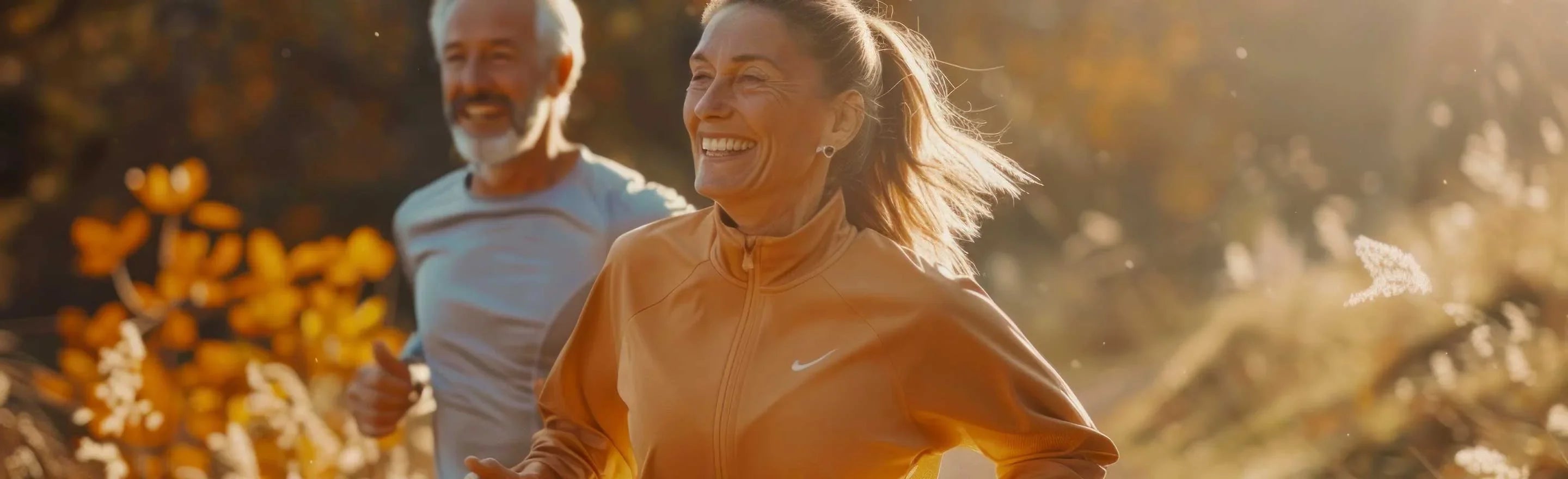 Active mature couple in a park at golden hour; amber herbal bottle in foreground, natural wellness and mobility.