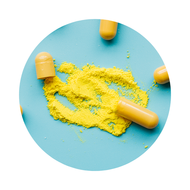 Open yellow capsule spilling fine herbal powder on cream background.