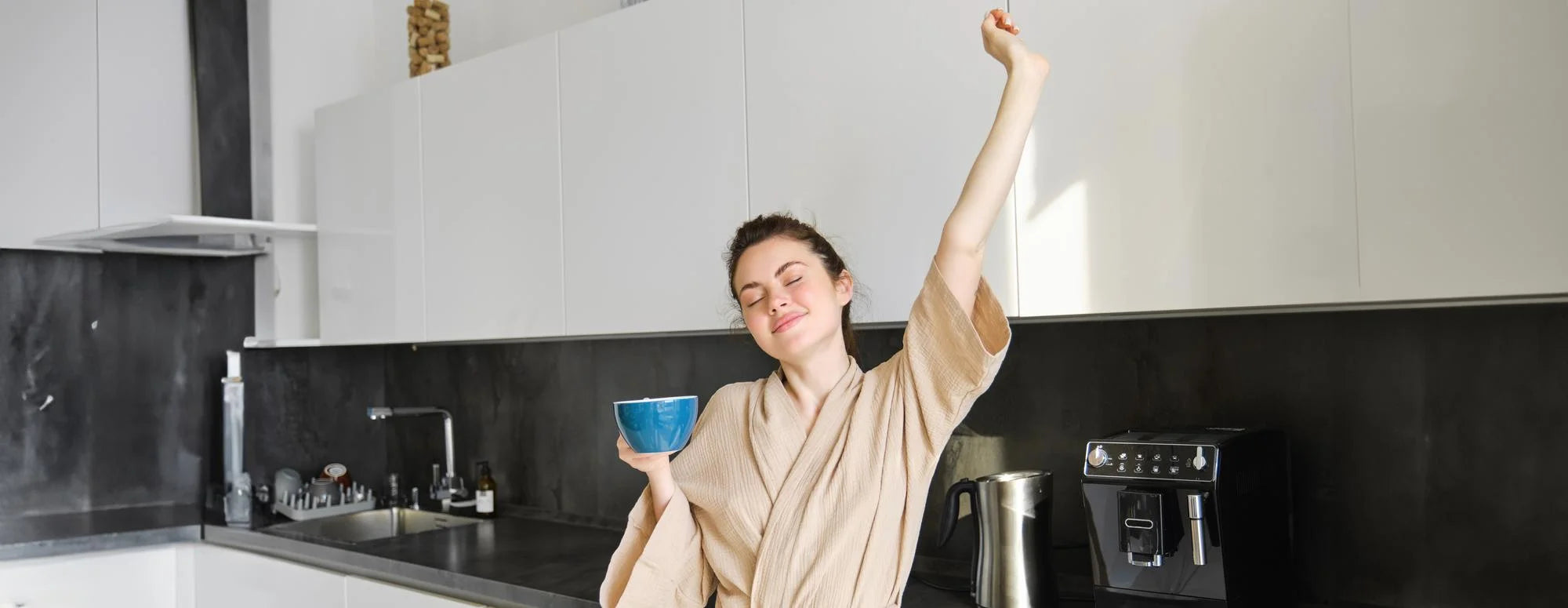 Morning kitchen scene with a person holding a glass of water and one capsule; pill bottle and honey on the counter, central negative space for the hero banner.