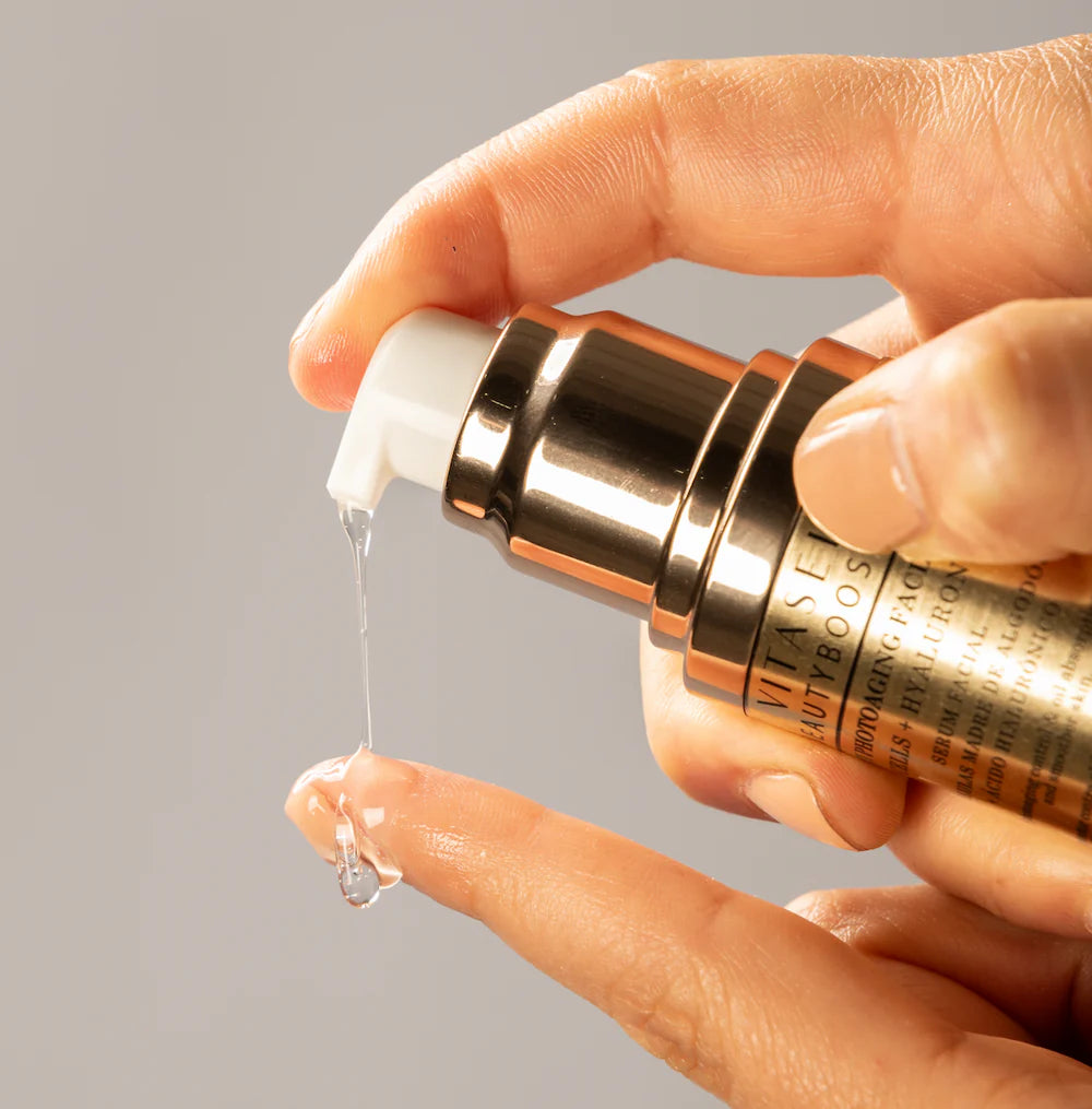 Texture shot—clear serum dispensed from airless pump onto fingertip.
